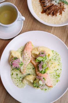 A delicious plate of salmon with vegetables, garnished in sauce, served with tea.