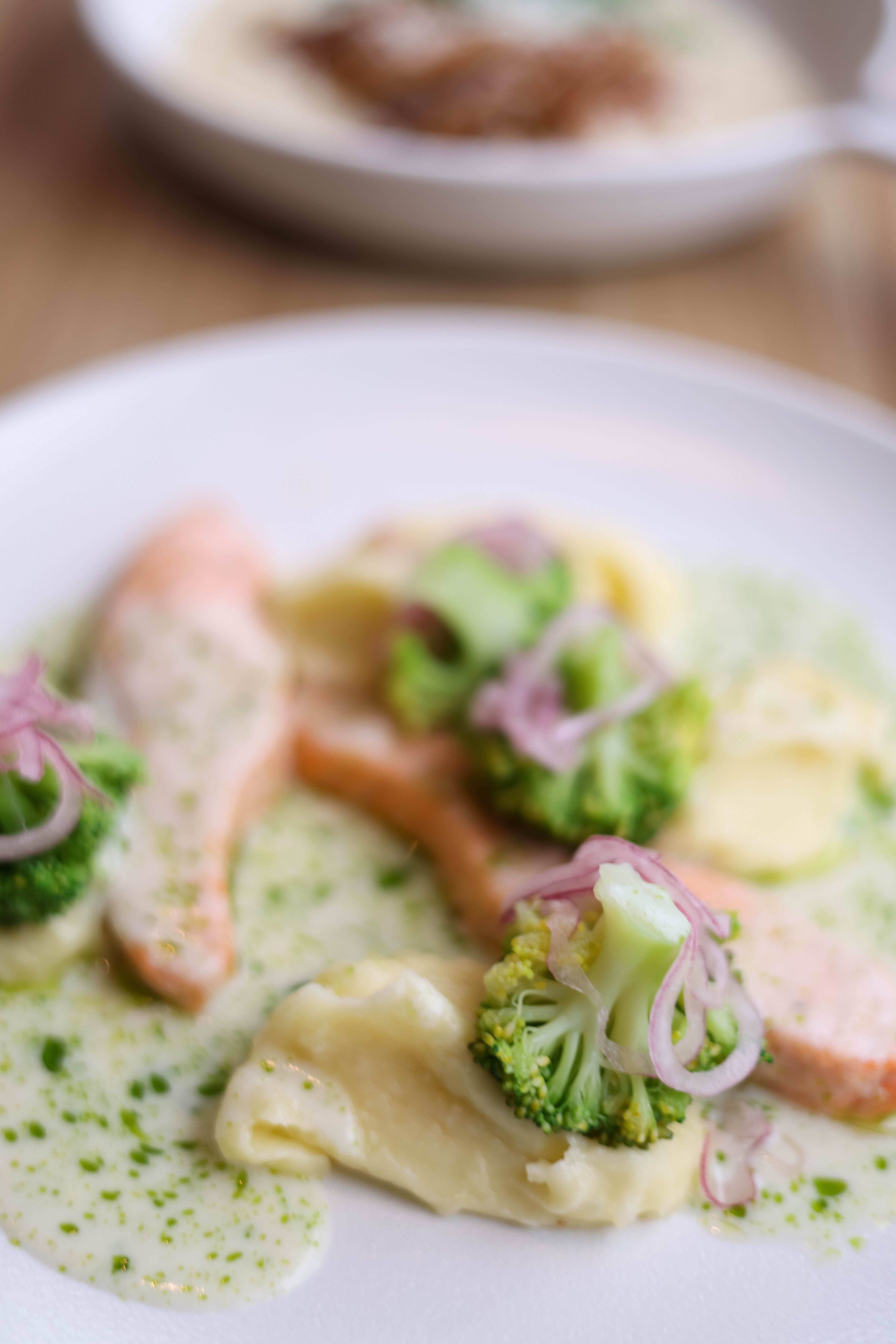 Close-up of a gourmet dish with salmon, broccoli, and mashed potatoes.