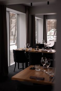 Modern dining room with elegant table settings and large windows providing natural light.