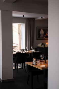 Sophisticated modern dining room with wooden tables and stylish glassware, ready for an elegant dining experience.