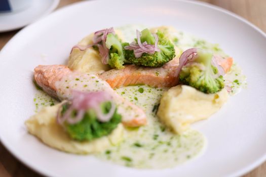 Delicious salmon served with broccoli, mashed potatoes, and creamy sauce.