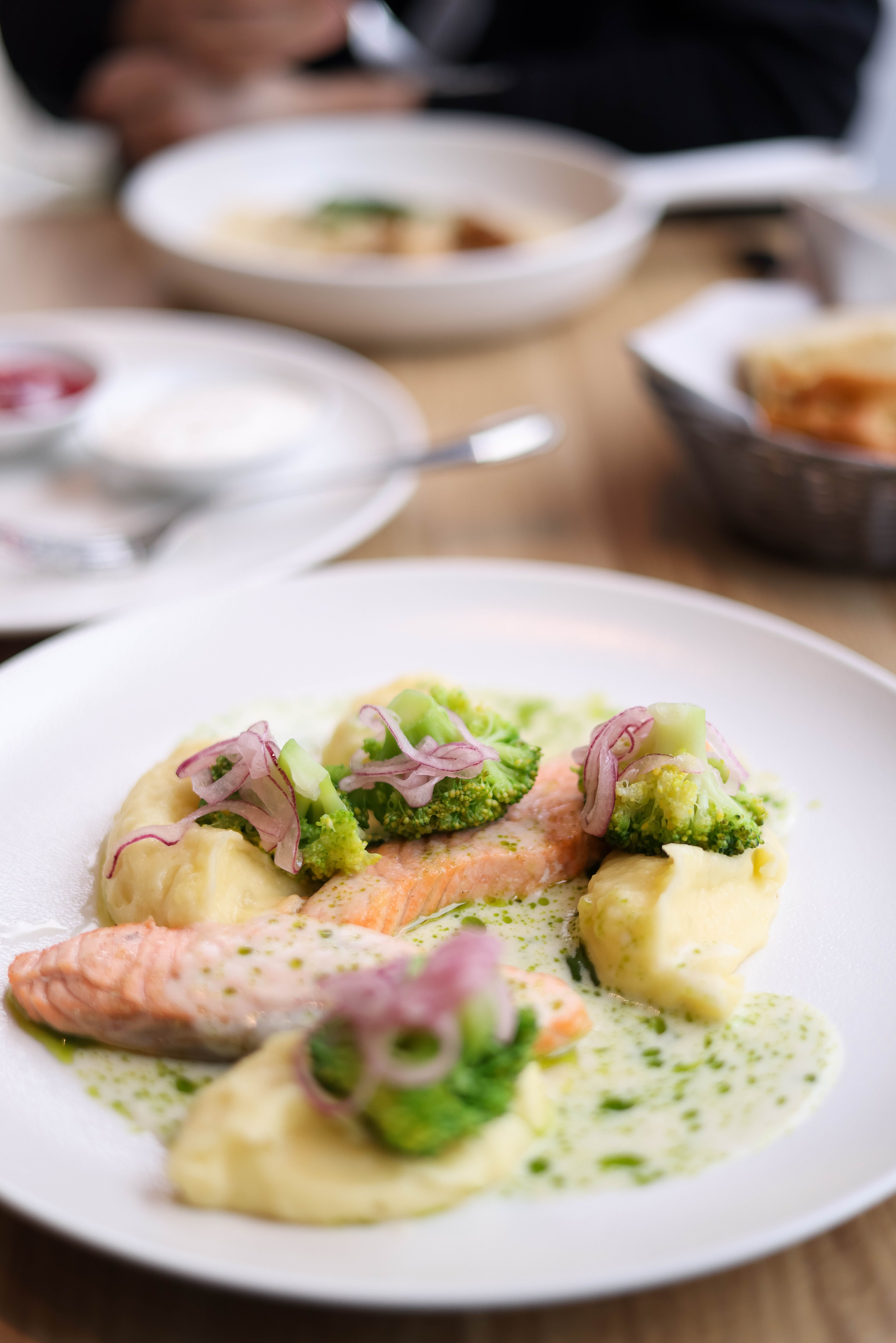 Delicious salmon fillet with broccoli and potatoes on a white plate, perfect for a fine dining experience.