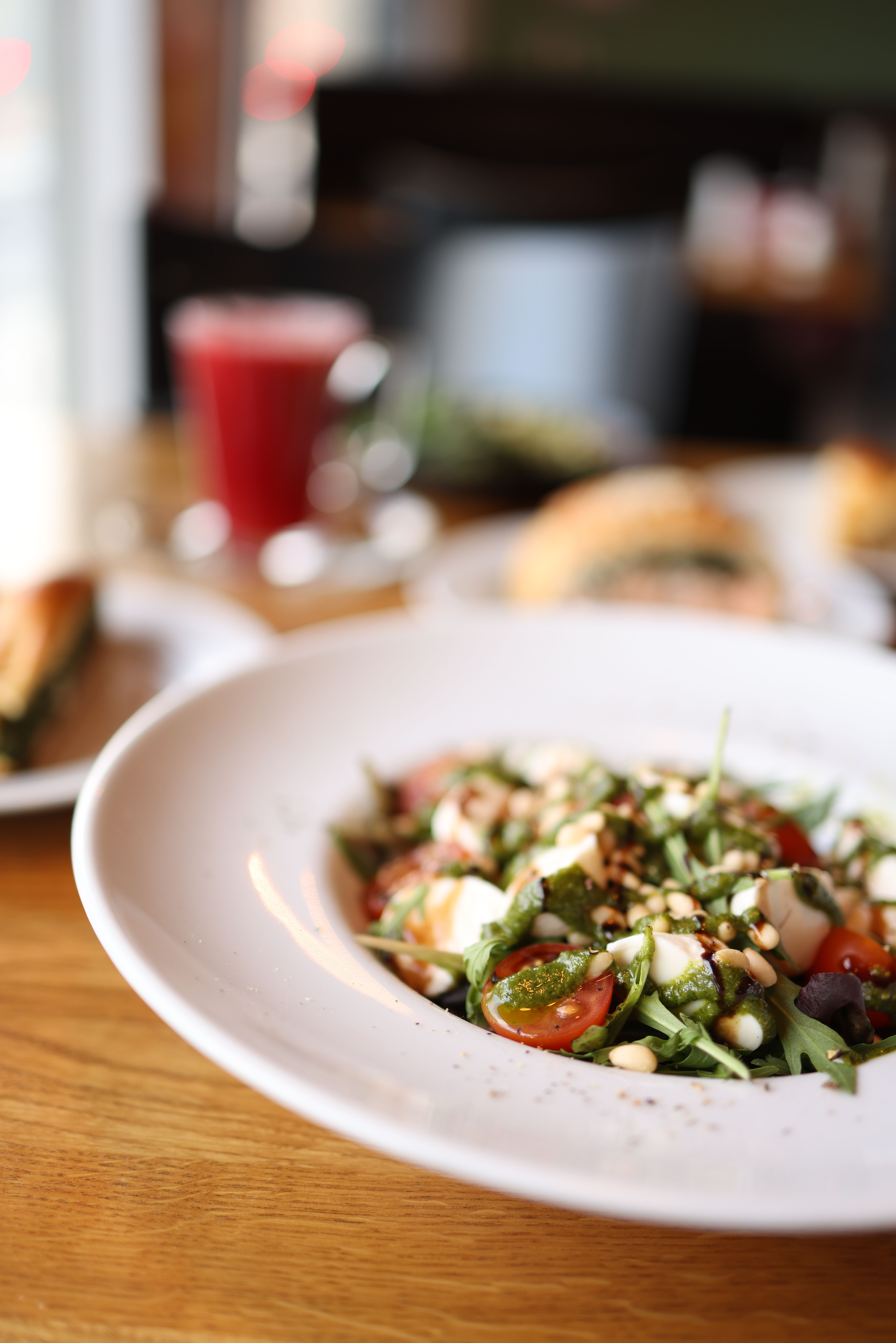 Close-up of a fresh arugula salad with tomatoes and pine nuts on a white plate indoors.