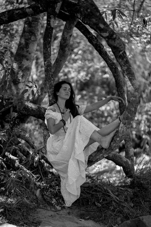 Grayscale Photo of Woman in White Dress Standing Near Tree