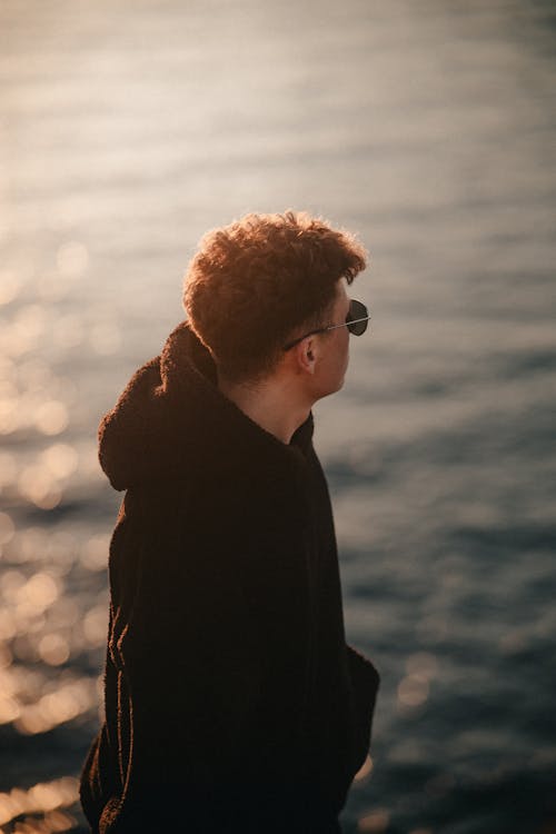 A man in a hoodie looking out over the water