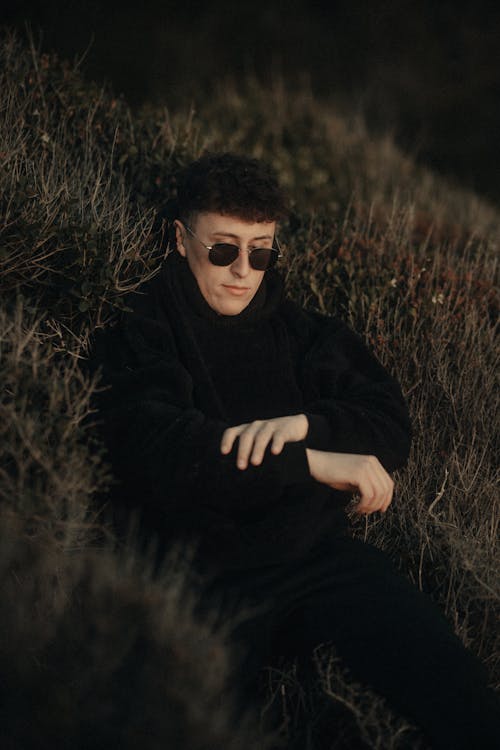 A man in black sunglasses sitting on the ground