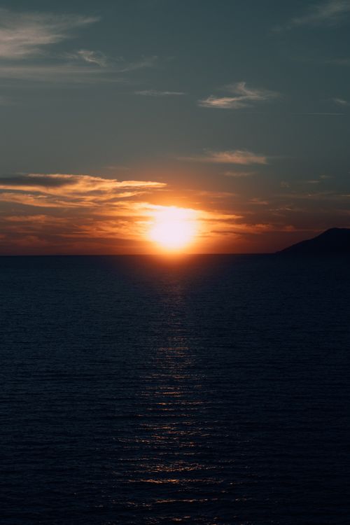 Free Beautiful ocean sunset with vivid hues reflecting on the water, creating a serene seascape. Stock Photo