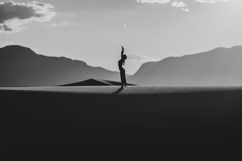 Silhouette of a Woman Standing with Her Arms Raised in a Desert 
