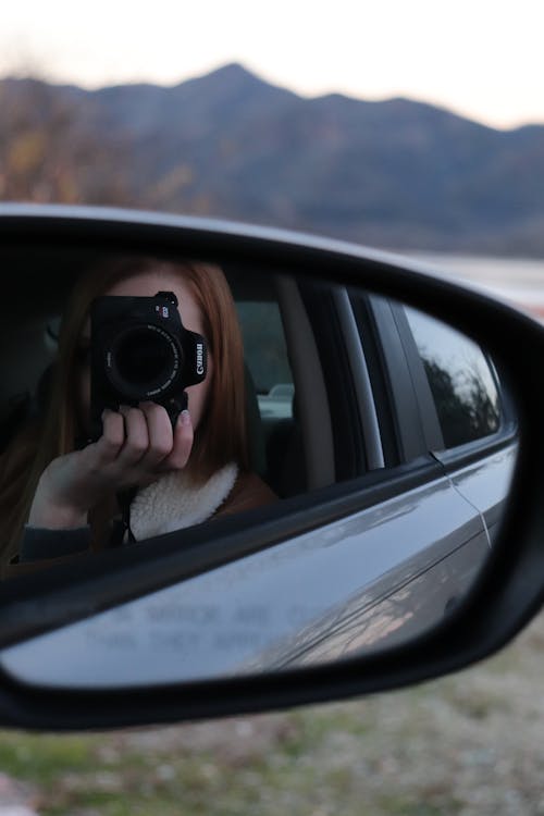 Reflection of Woman with Camera in Car Mirror