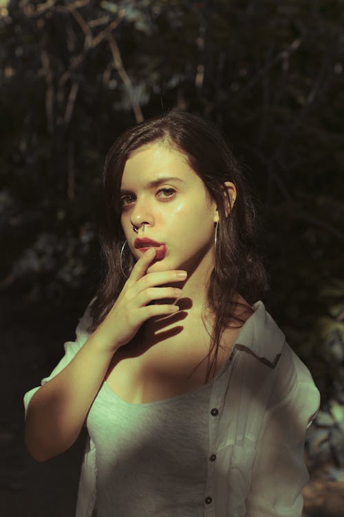 Woman in White Blazer Touching Her Lips While Standing