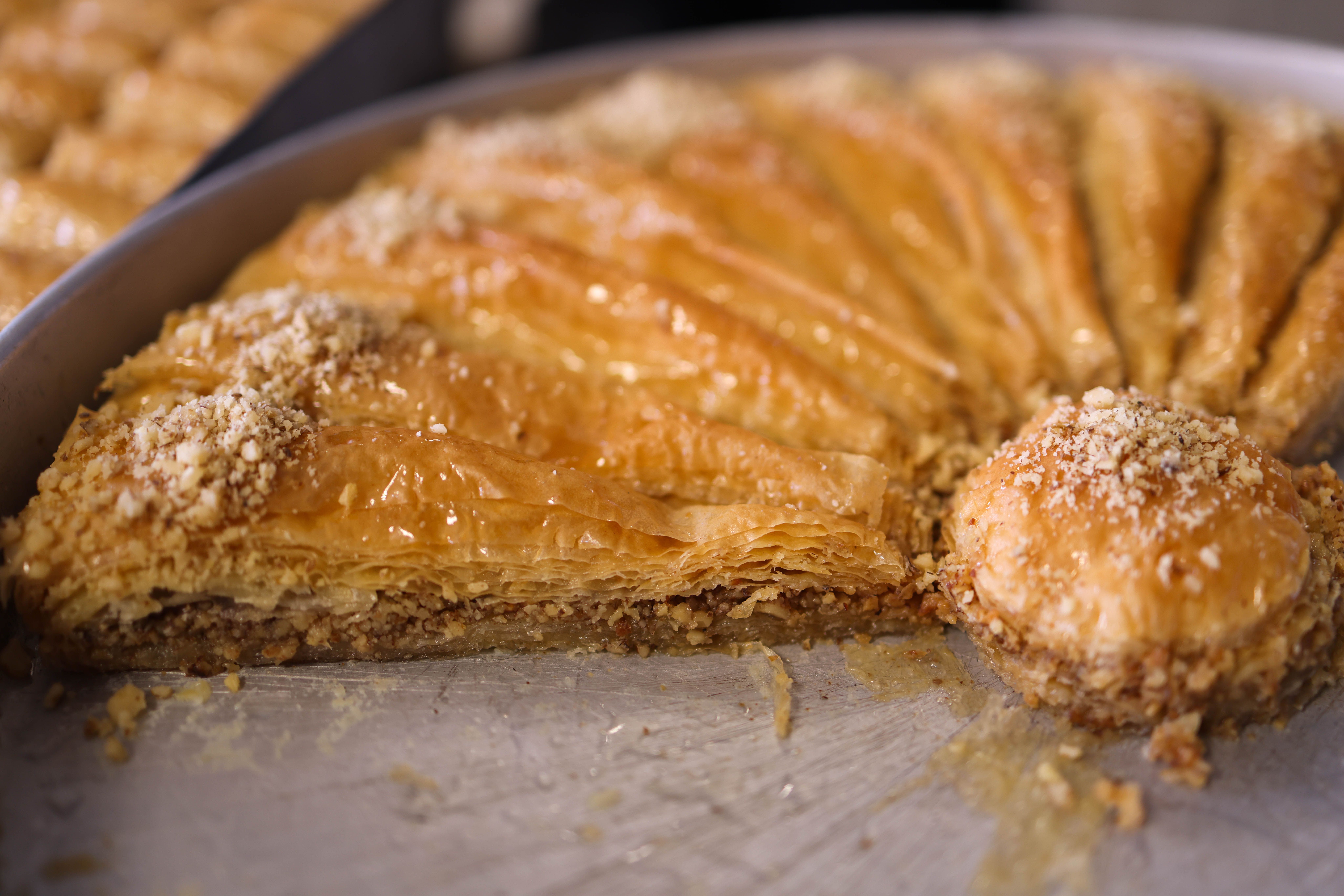 A tray of diamond-cut baklava glistening with honey syrup and crushed pistachios
