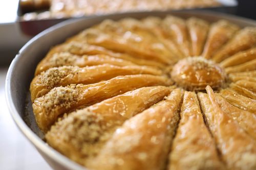 Free Close-up of a round baklava tray with sliced filo pastry topped with nuts, perfect for dessert lovers. Stock Photo