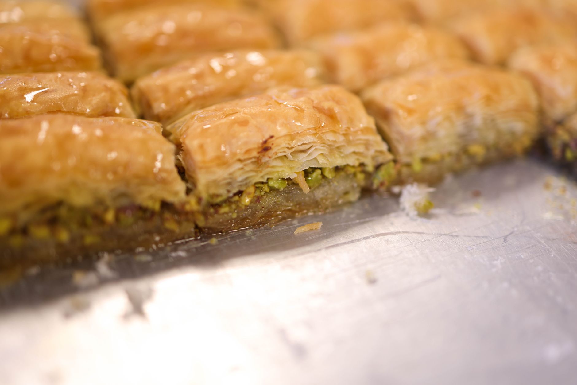 Slice of Pistachio Greek Honey Cake drizzled with honey and garnished with pistachios