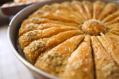 Free Close-up view of freshly baked round baklava topped with chopped nuts and honey. Stock Photo