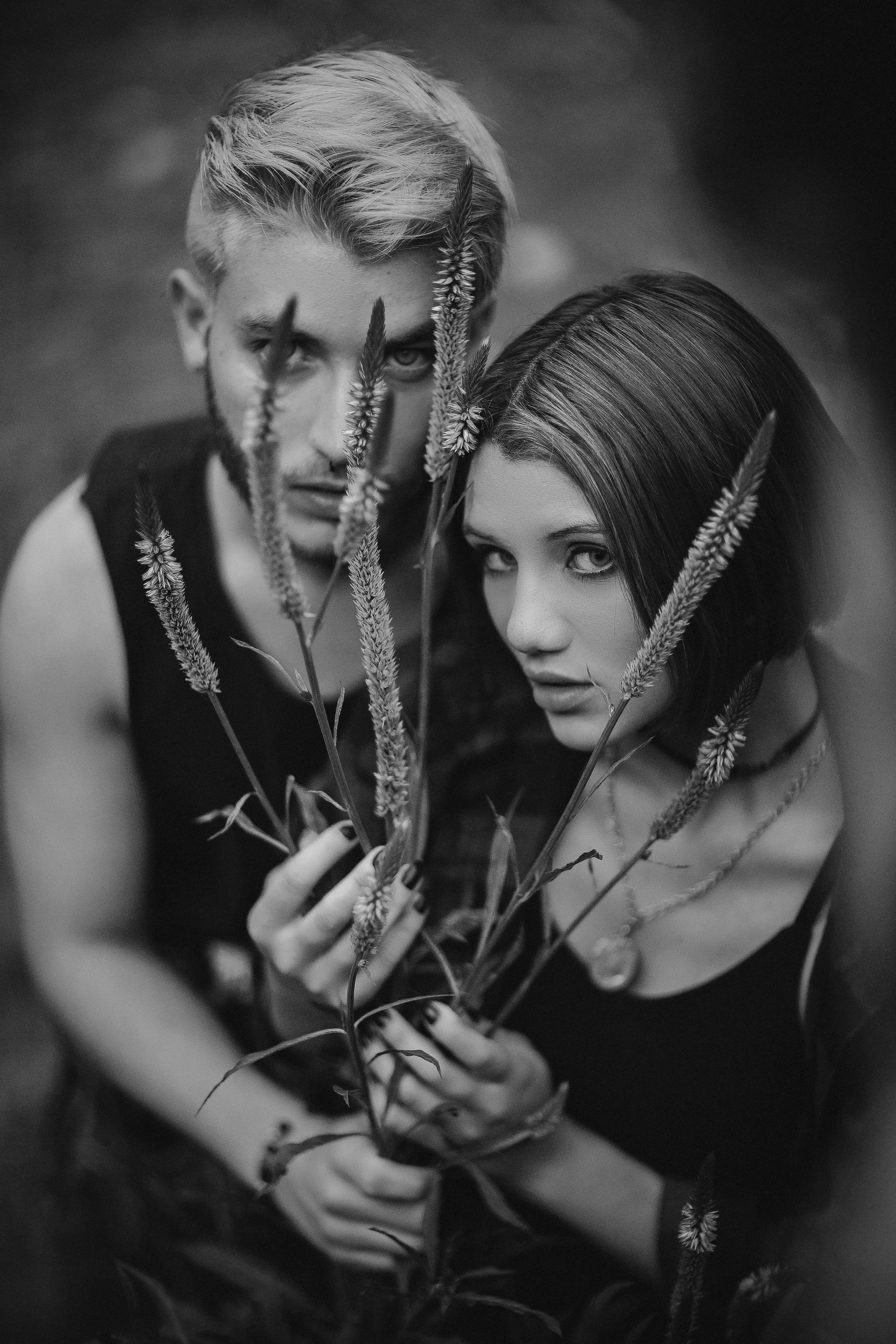 一对男女手持高大植物的黑白肖像引人注目，传达出神秘而艺术的氛围