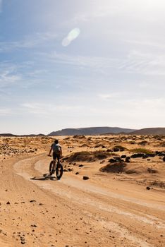 A man rides a fat-tire bike through the desert landscape of Lanzarote, capturing adventure and exploration.