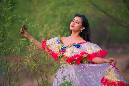 A woman in a colorful dress posing in the woods