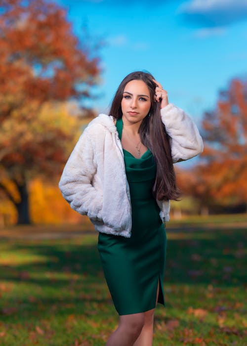 A woman in a green dress and fur coat posing for a photo