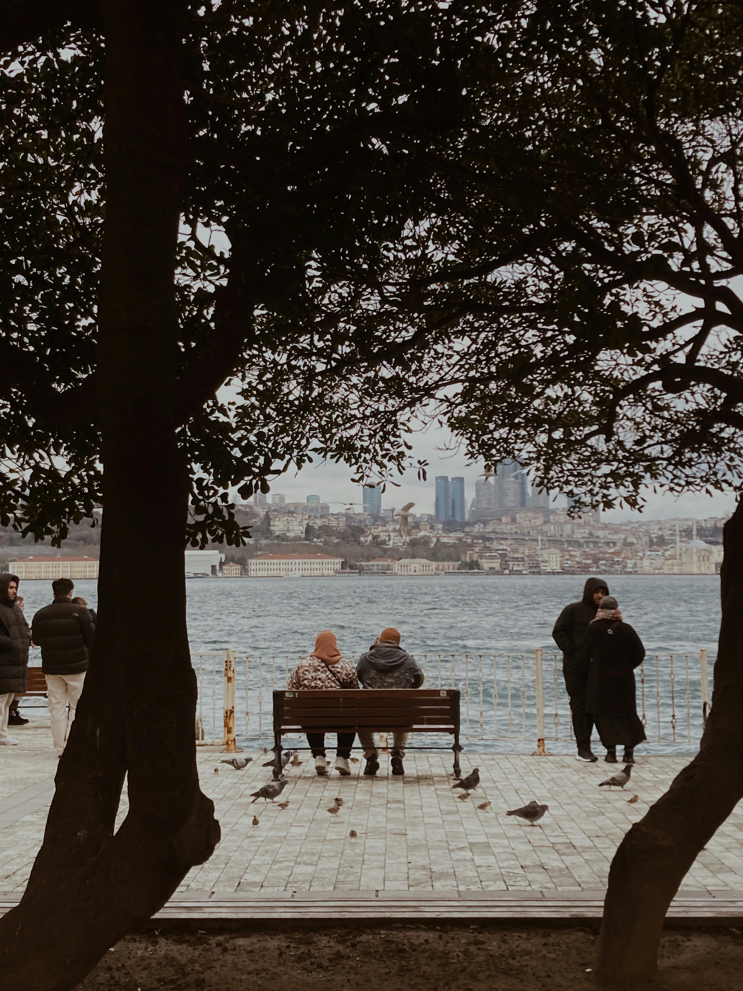 Charming view of people relaxing by the Bosporus with an urban skyline in the background.