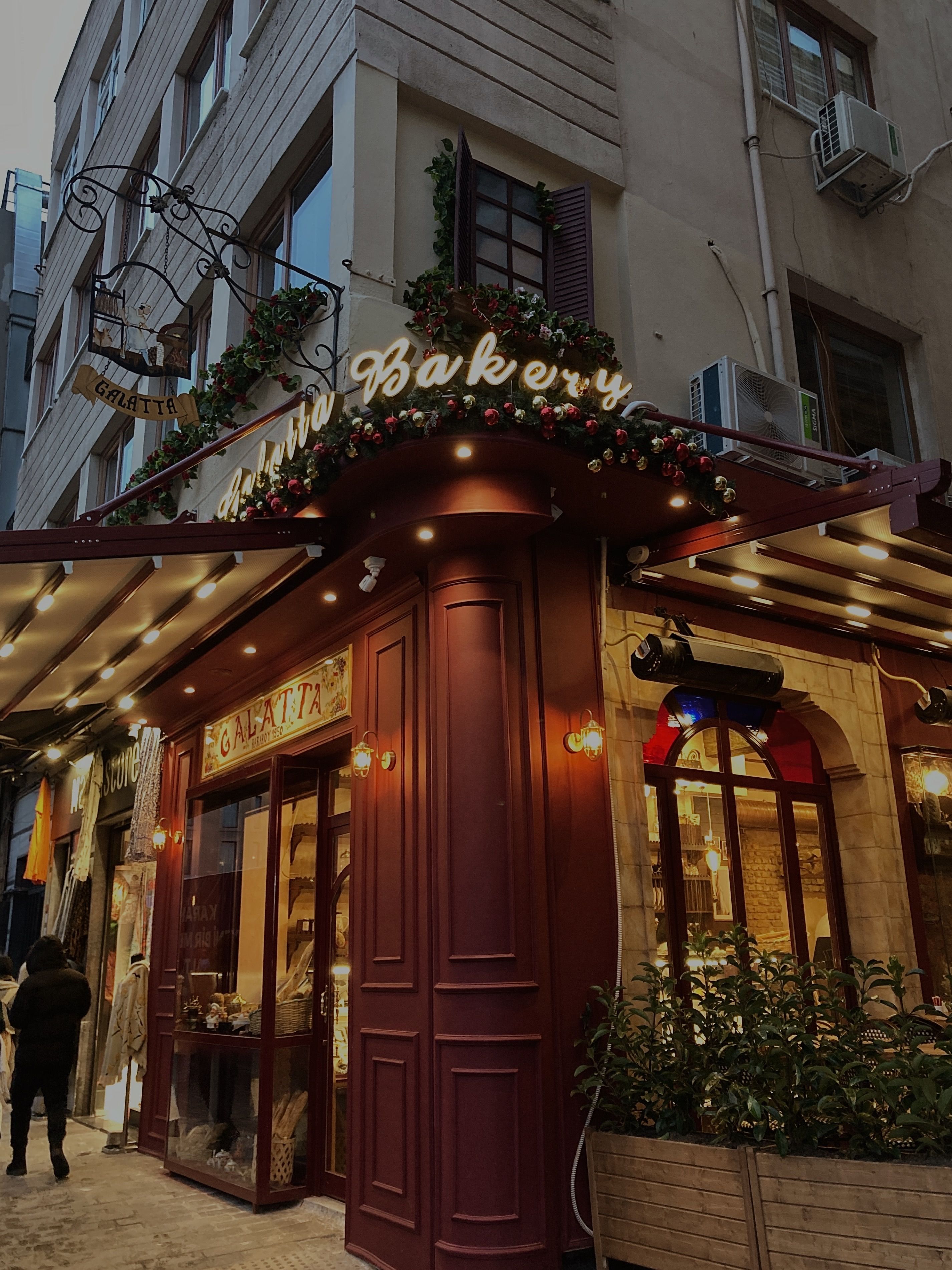 cozy little European neighborhood bakery storefront with warm light and flowers