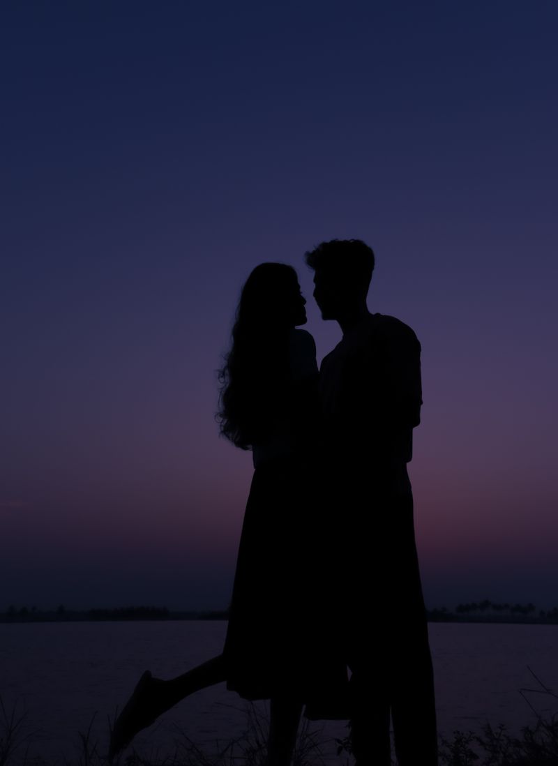 Silhouette of a Couple Holding Hands by a Body of Water at Sunset ...