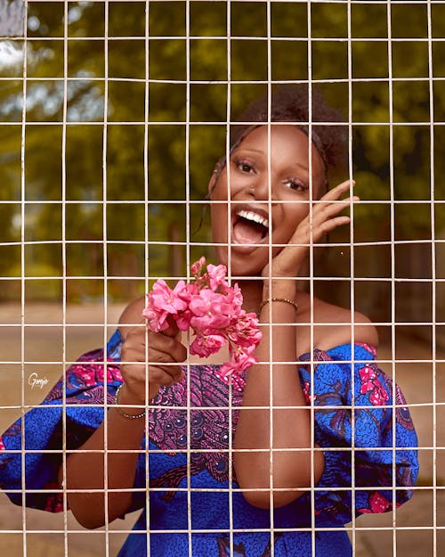 Young, Elegant Woman Standing behind a Fence and Smiling 
