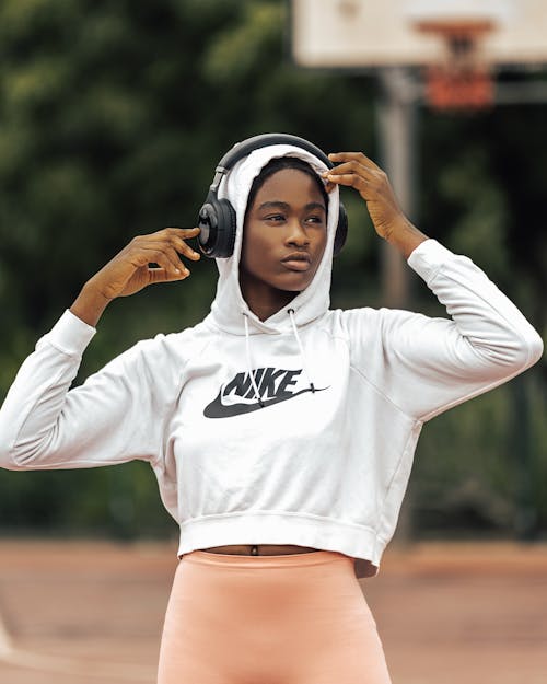 Young Woman in Sports Clothing and Headphones Standing Outside 