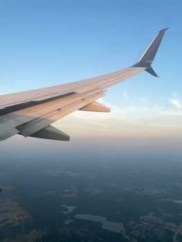 View of airplane wing with scenic aerial landscape during day flight.