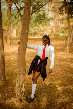 Teenage girl poses in school uniform outdoors, showcasing fashion and confidence.