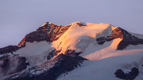 Free Snow-capped mountain peak glowing with warm sunset hues, showcasing nature's majesty. Stock Photo