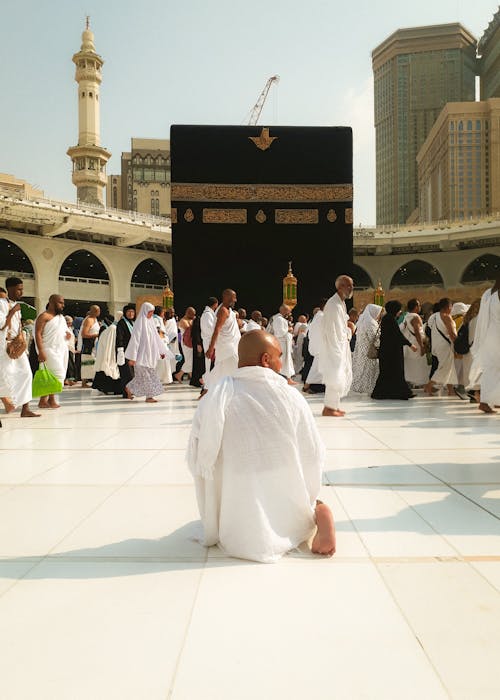 Man Kneeling and Pilgrims Walking at Great Mosque in Mecca