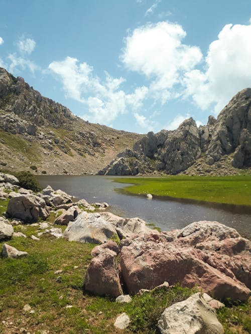 A lake surrounded by rocks and grass in the mountains