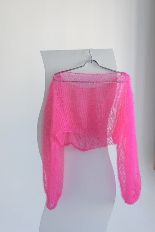 A pink sweater hanging on a white wall