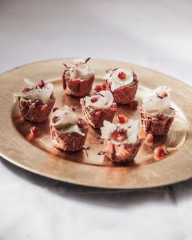 Close-up of decorative mini desserts with whipped cream on a gold plate.