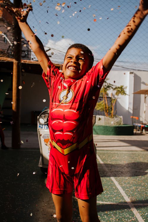 Boy in Flash Costume Standing with Arms Raised