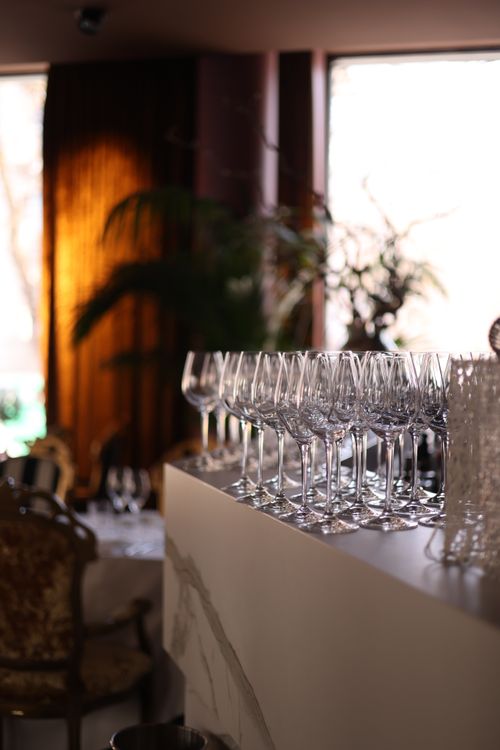 Free Sleek restaurant interior showcasing a row of clean wine glasses under ambient lighting. Stock Photo