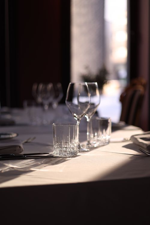 Free A beautifully arranged table with wine glasses and tumblers in a sunlit restaurant setting. Stock Photo