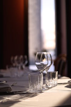 Sunlight casts a warm glow on a refined table setup with wine glasses in a cozy restaurant.