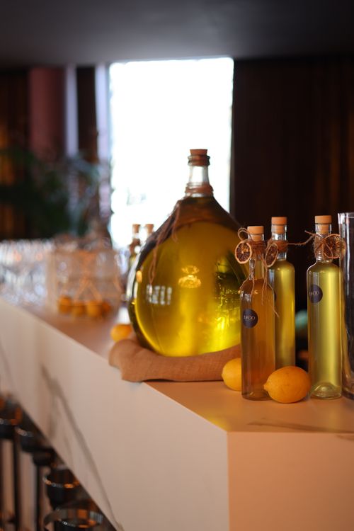 Free Close-up of olive oil bottles and lemons on a shelf with warm lighting. Stock Photo