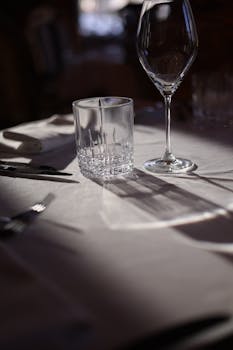 A classy table set with wine and water glasses casting shadows in the sunlight.