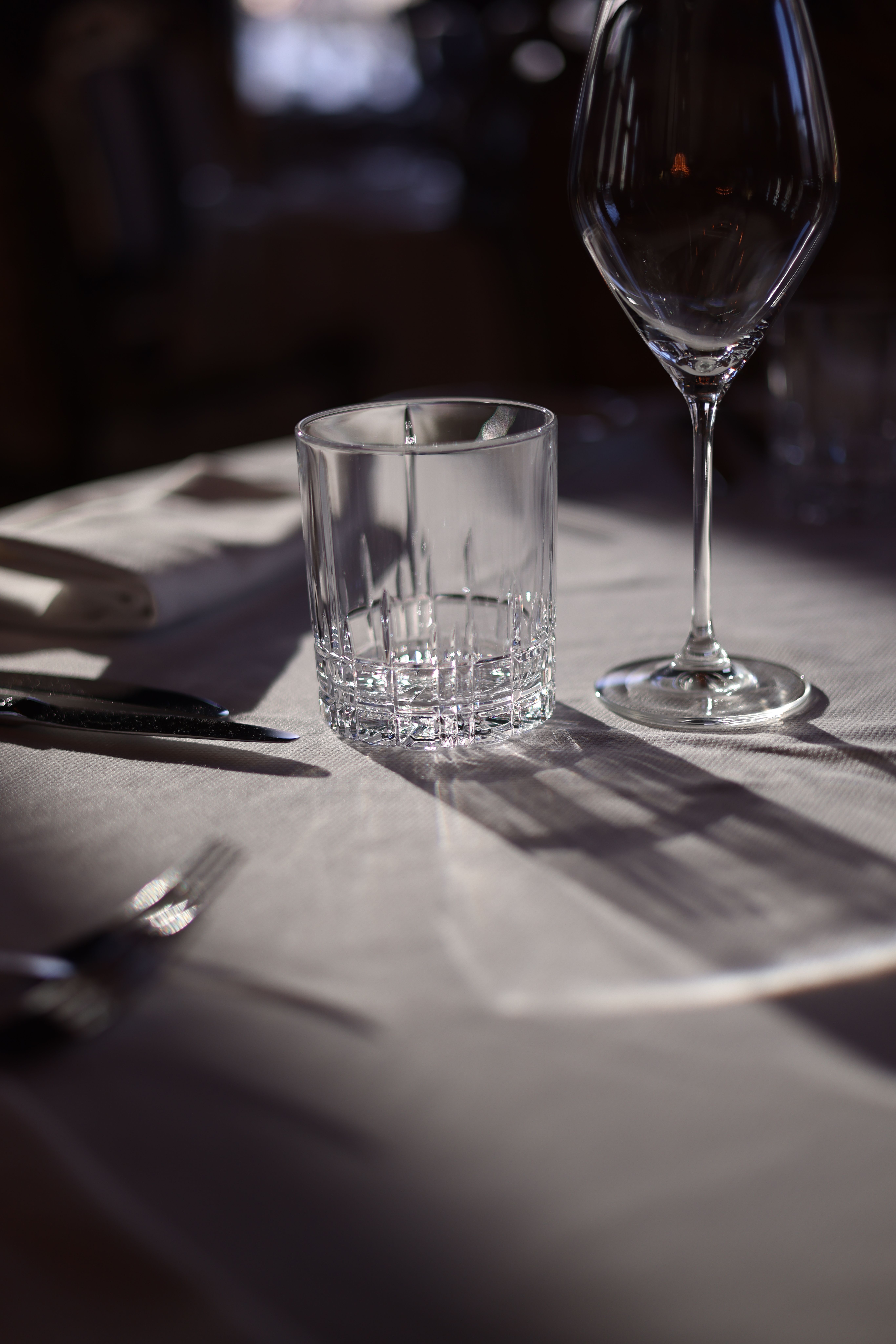 A beautifully lit dining table setup with glassware and cutlery in a restaurant setting.
