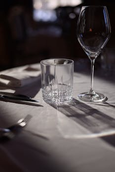 Close-up of elegant table setup in a restaurant featuring glassware and tableware under ambient light.