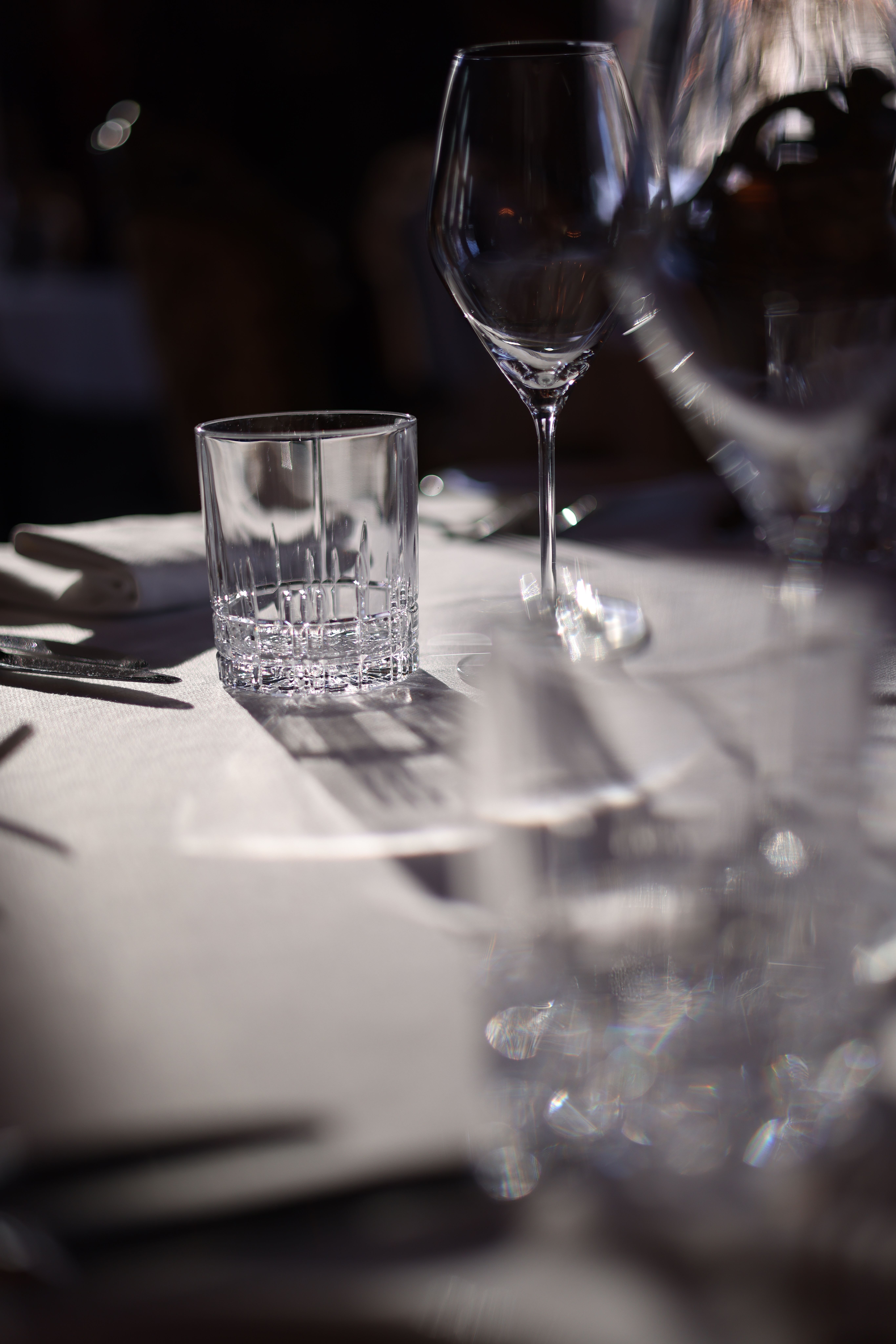 Close-up of a beautifully set table with a focus on clear glassware and soft lighting.
