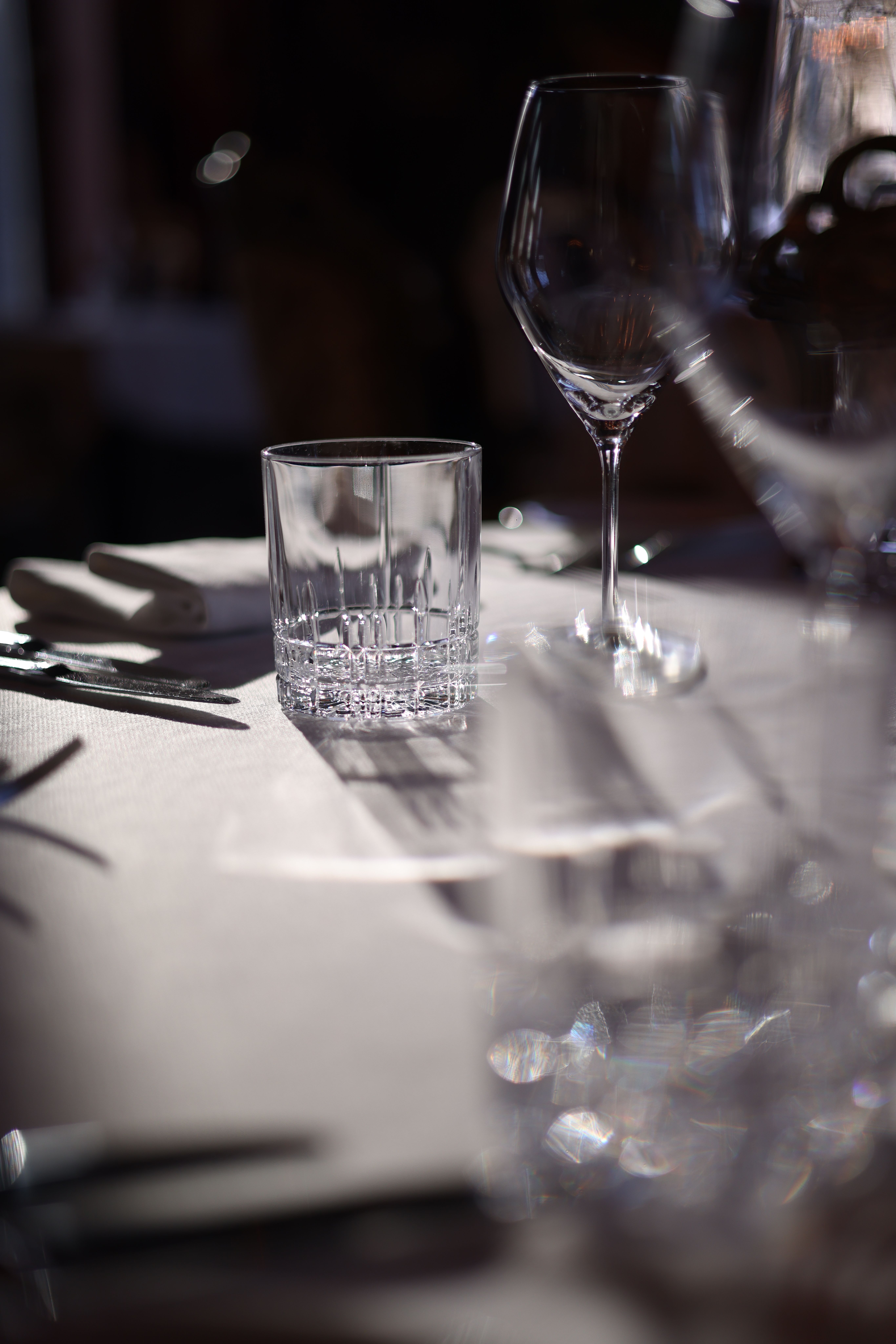 Elegant dining table with wine glasses and sunlit ambiance in a restaurant.
