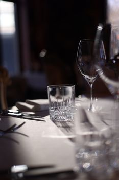 A sophisticated table setting with sunlit glasses and cutlery on a white tablecloth.