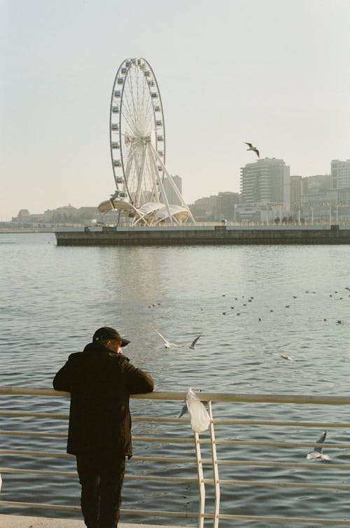 Man Standing on Baku Boulevard with Ferris Wheel behind