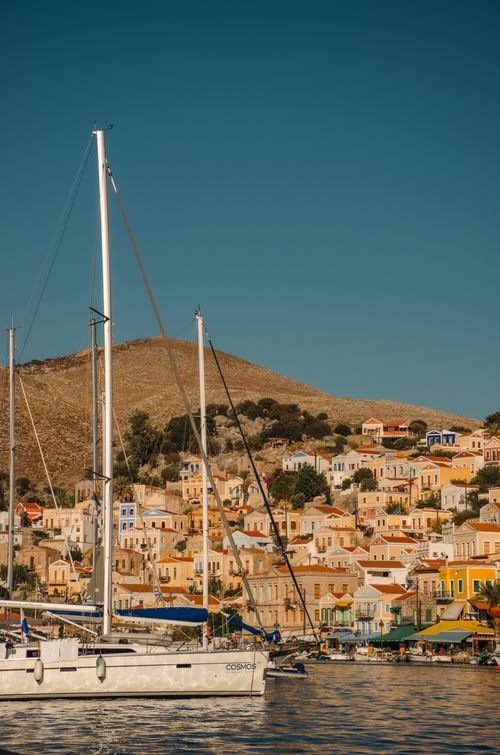 Free Colorful houses and sailboats on Symi Island's scenic harbor under a clear sky. Stock Photo