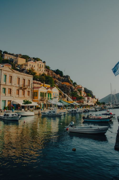 Free Charming harbor scene on Symi Island, Greece, featuring colorful buildings and boats at sunset. Stock Photo