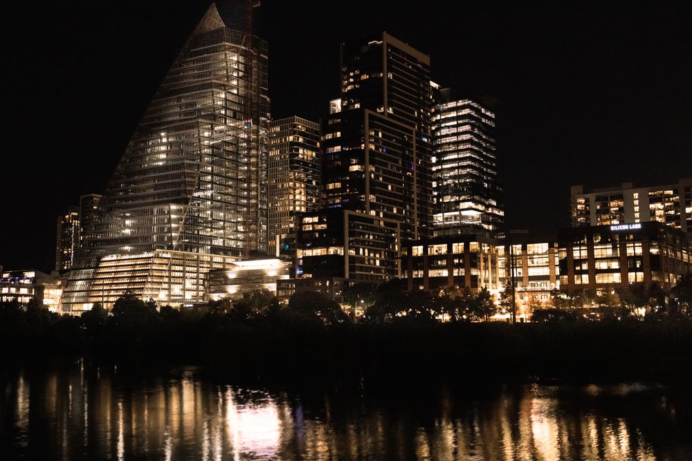 Illuminated skyscrapers reflecting in the river at night in downtown Austin, Texas.