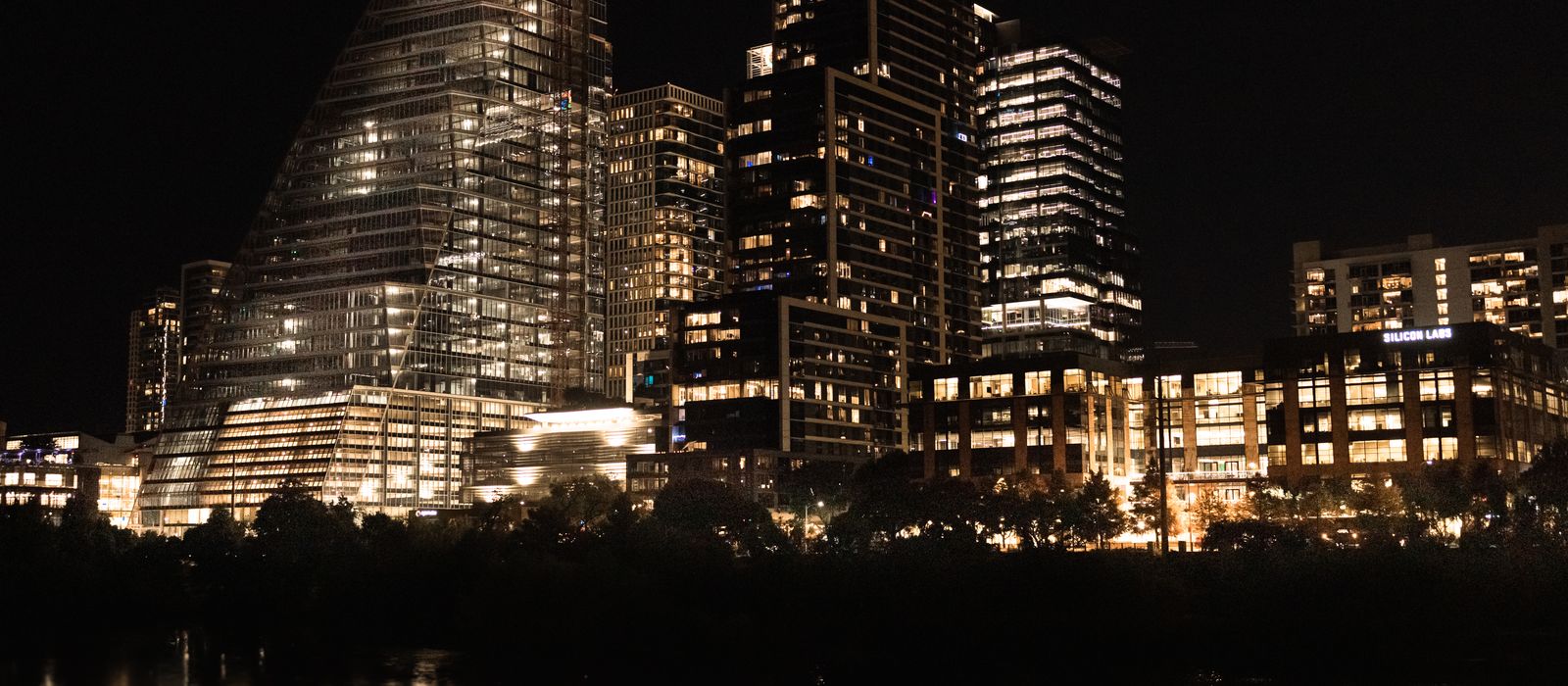 Illuminated skyscrapers reflecting in the river at night in downtown Austin, Texas.